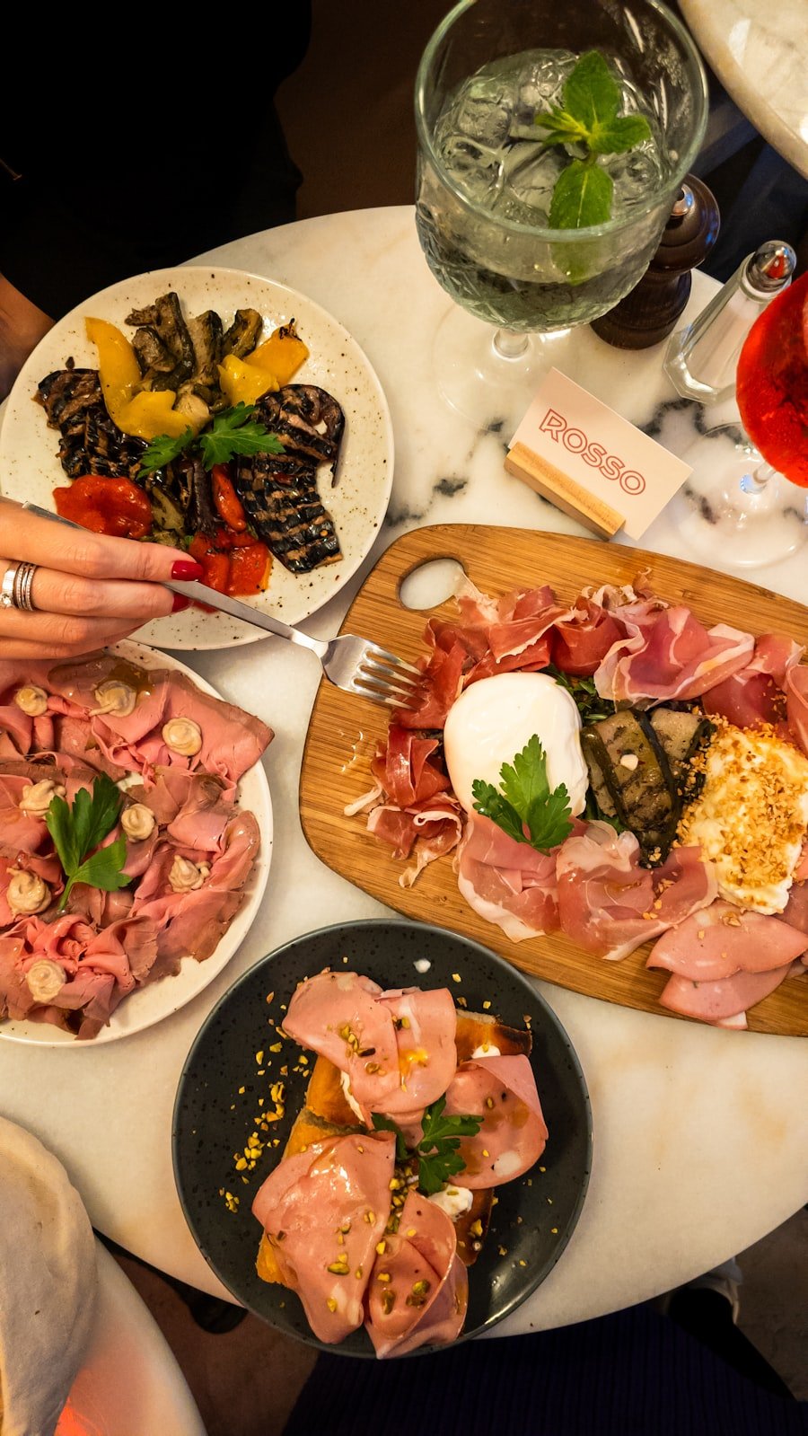 A sunlit Italian table set with plates of antipasti and wine